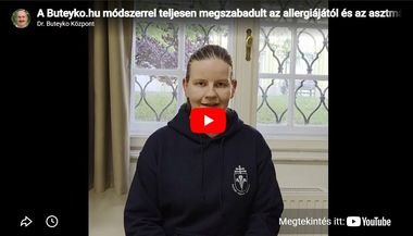 drDávid Dorottya 380x217 - Dr. Buteyko Központ - NEM ONLINE, élő tanfolyamok országszerte. Orvos oktatók. Video thumbnail: woman in a navy hoodie with an emblem sits indoors by a window; YouTube play button overlay.